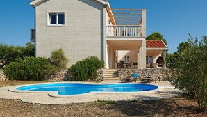 A two-story house with a swimming pool, stone walls, and a balcony with outdoor furniture. - Modern four-bedroom Villa Nella with private pool and beautiful sea view (Stari Grad)
