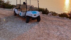 A golf cart parked on a gravel path by a lake at sunset. - Modern four-bedroom Villa Nella with private pool and beautiful sea view (Stari Grad)