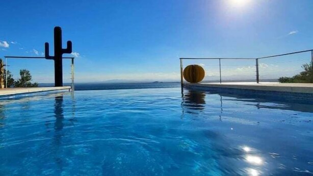 A clear blue pool with a cactus sculpture and a round wooden object on the edge. - Villa Alco in Roses with beautiful sea views AV-68 (Rosas / Roses)