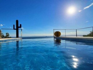 A clear blue pool with a cactus sculpture and a round wooden object on the edge. - Villa Alco in Roses with beautiful sea views AV-68 (Rosas / Roses)