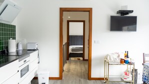 Une chambre d’hôtel équipée d’une kitchenette, d’un lit, d’une télévision et d’une petite table sur laquelle se trouvent divers objets.