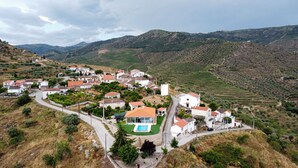 Un village perché sur une colline, avec des vignobles en terrasses, des maisons blanches aux toits rouges et une piscine.
