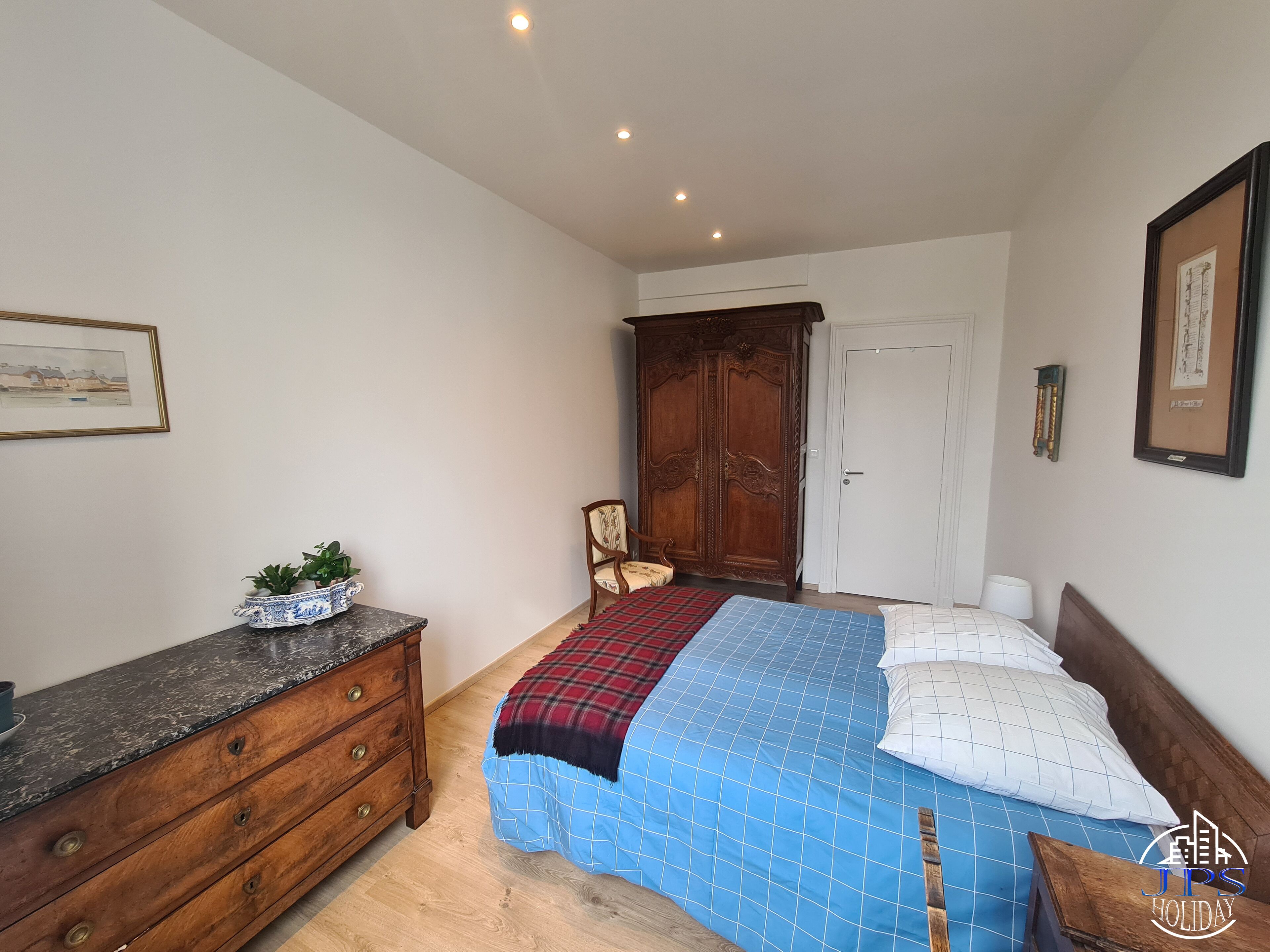 Une chambre à coucher avec un lit, une commode, une armoire et un tableau encadré au mur.