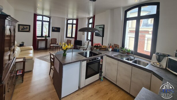 A modern kitchen with a central island, built-in oven, and a large window.