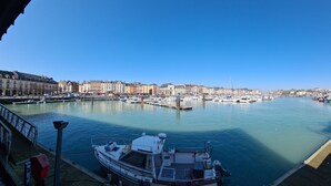 A marina with boats docked, a clear sky, and buildings in the background.