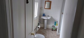 A small bathroom with a toilet, sink, and window.