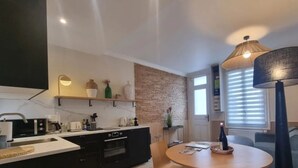 Ett modernt kök med en tegelvägg som accent, en matplats med ett runt bord och en stor golvlampa.