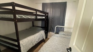 Ein Zimmer mit zwei Etagenbetten, einem Einzelbett, einem Sessel und einer Tür.