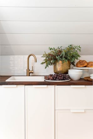 Enjoy cooking in this kitchen with a sleek countertop, brass faucet, and ample storage.