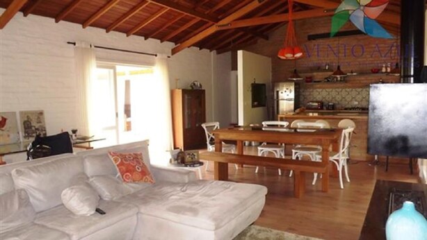 A spacious living area with a wooden ceiling, a dining table with chairs, and a kitchen in the background. - Beautiful single-story house, super cozy: 3 suites. (Monte Verde)