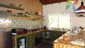 A kitchen with a brick wall, green cabinets, a built-in oven, and a window providing natural light. - Beautiful single-story house, super cozy: 3 suites. (Monte Verde)