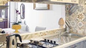 Una cocina moderna con estufa a gas, pileta de acero inoxidable y zócalos decorativos.