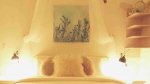 Una camera da letto con un letto a baldacchino, un quadro appeso al muro e un comodino con una lampada.