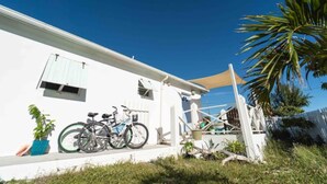 Un edificio bianco con un portico, biciclette e una palma.