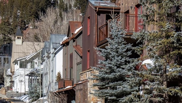 A wooden building with a stone base, a balcony, and a view of a snow-covered mountain.