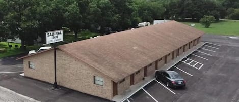 A Sabinal Inn building with a brick exterior, a parking lot, and a signboard.