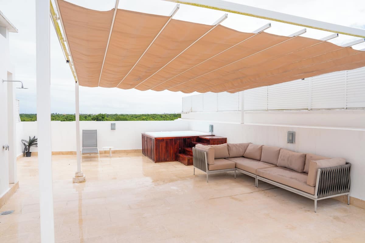 A covered outdoor area with a sofa, a table, and a radiator.