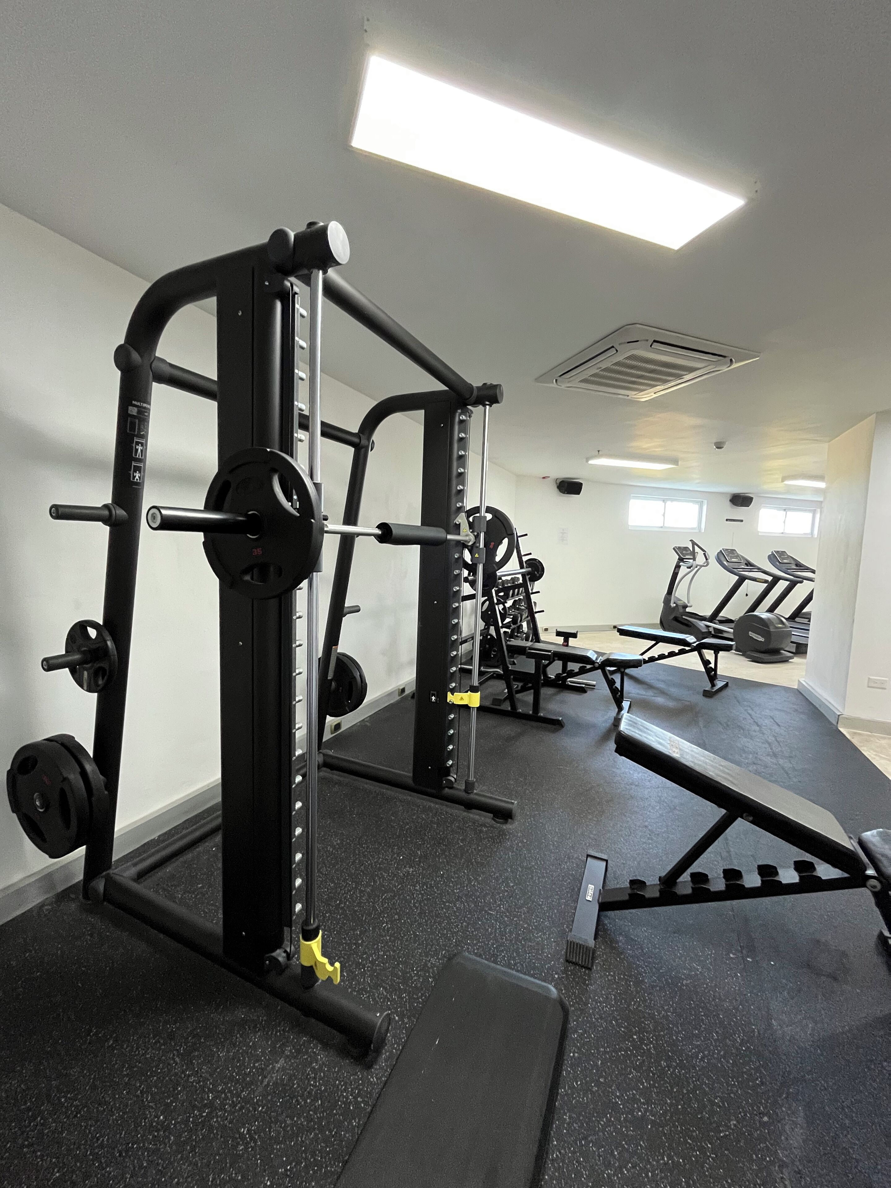 A gym with weightlifting equipment, treadmills, and a bench.