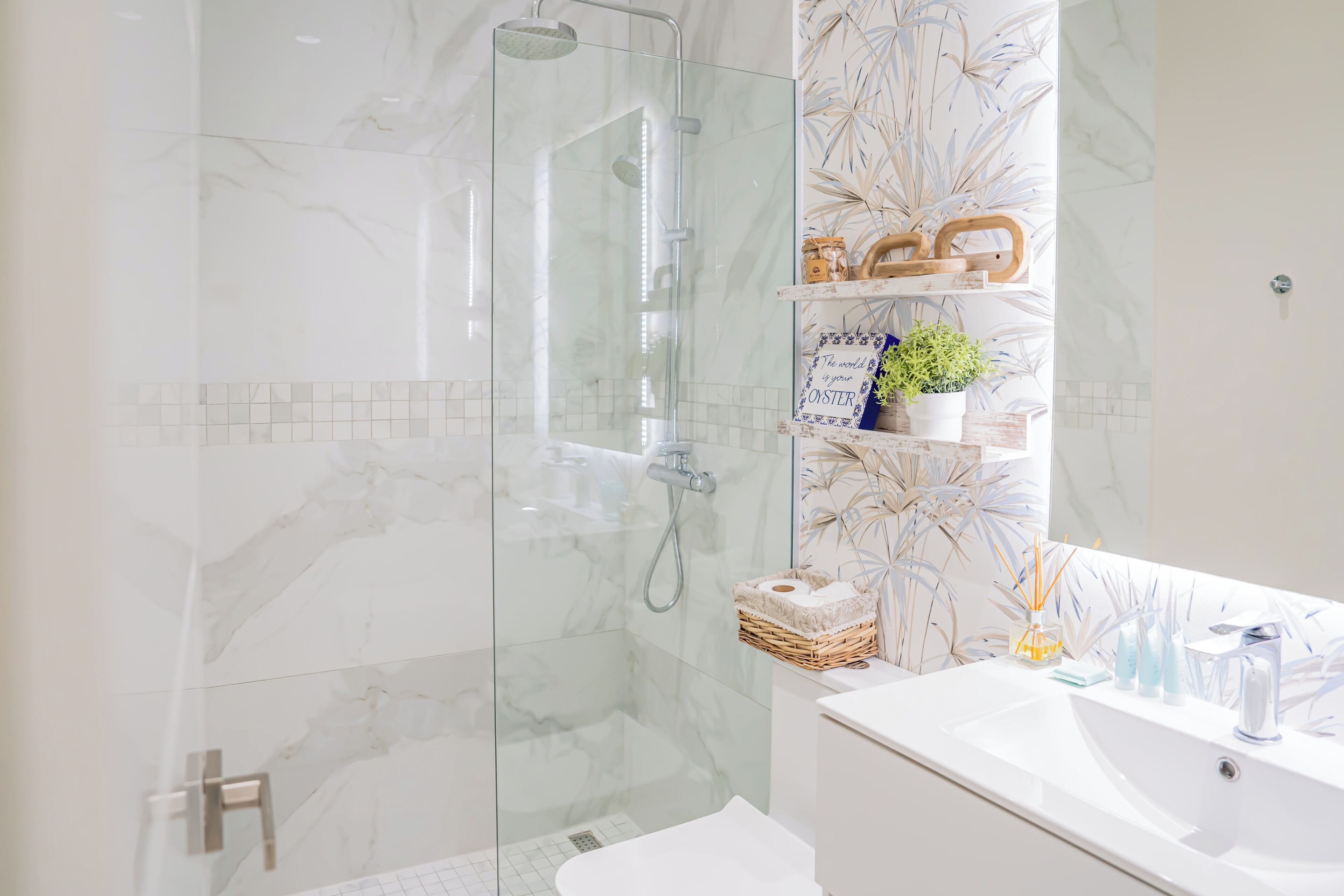 A modern bathroom with a glass-enclosed shower, marble walls, and a white vanity with a mirror.