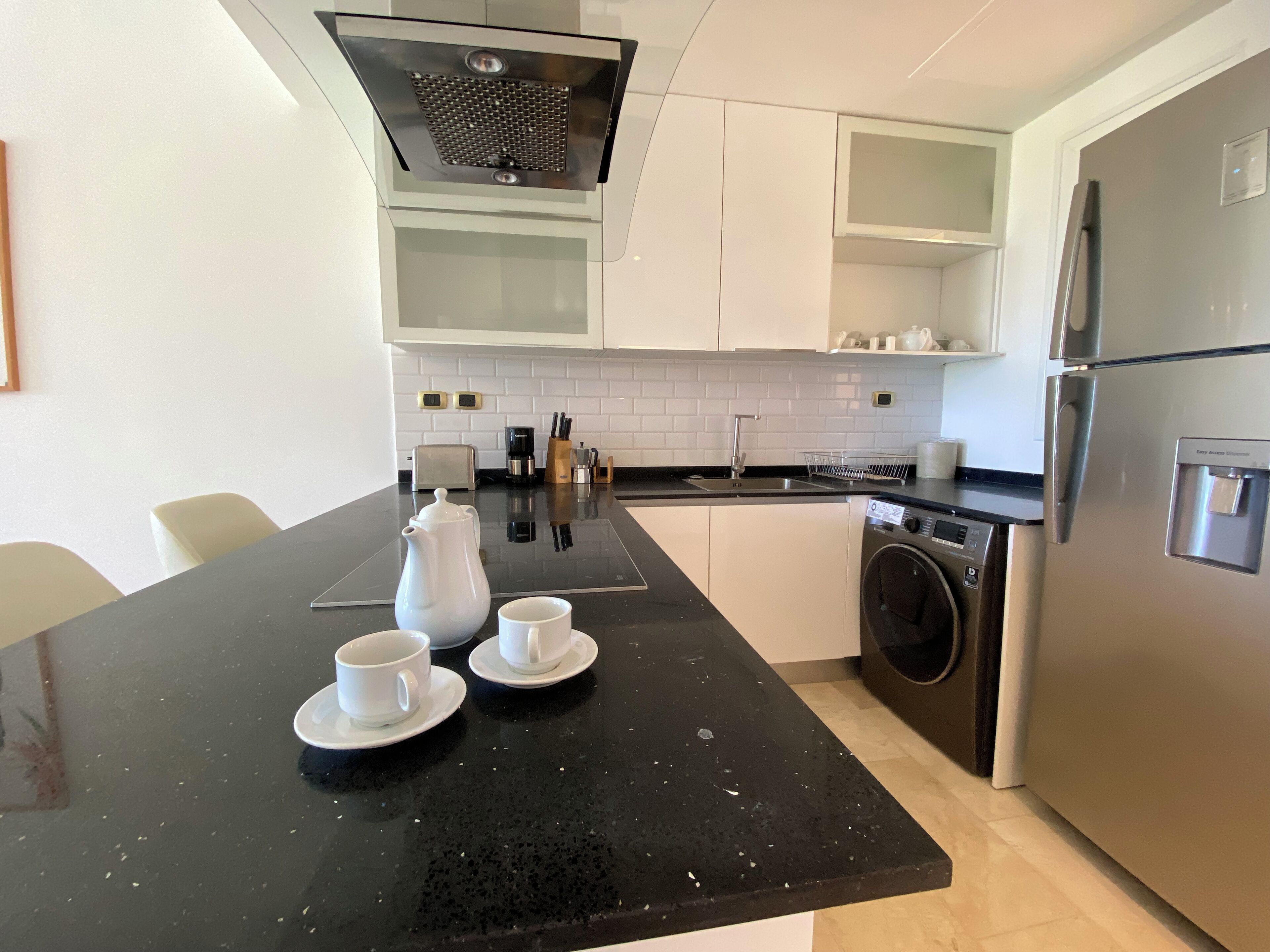 A modern kitchen with a black countertop, stainless steel appliances, and white cabinetry.