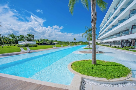 Una piscina al aire libre, sombrillas, sillones reclinables de piscina