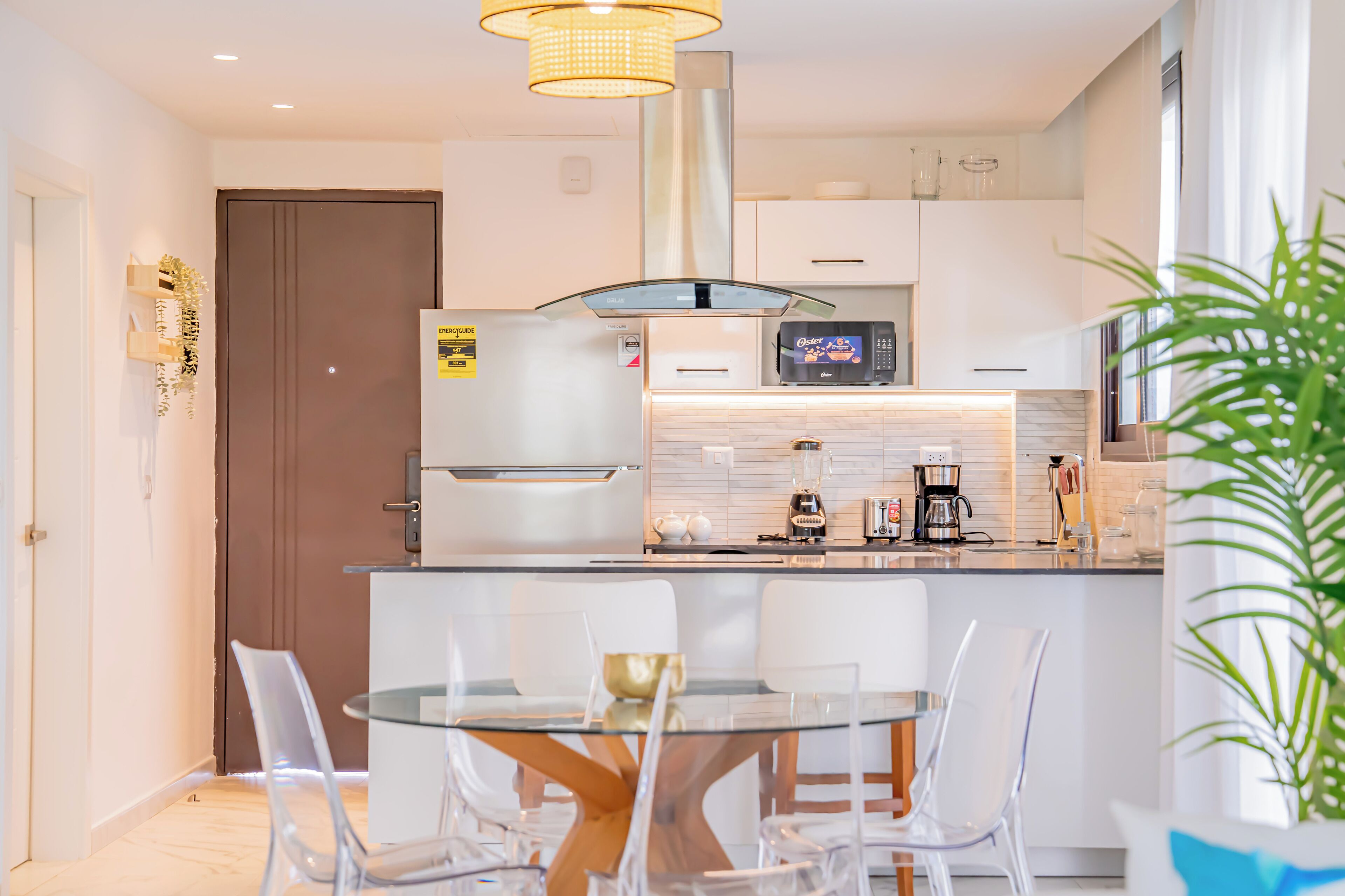 A modern kitchen with a central island, stainless steel appliances, and a glass dining table with chairs.