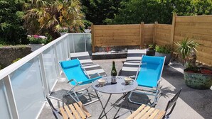 A patio with a glass enclosure, outdoor seating, and potted plants. - Maison typique pour 4 personnes, jardin clos et fleuri, proche plage (Treffiagat)