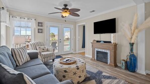 A living room with a sofa, chairs, a TV, a fireplace, and a ceiling fan. - Heart of Oak Island/2nd Row Ocean Vew - 3 Bedrooms (Oak Island)