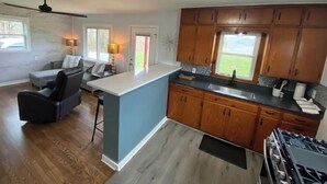 A modern kitchen with wooden cabinets, a central island, and a built-in stove. - Moonlight on the White- Fayetteville river cabin (Springdale)