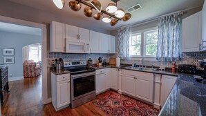 A modern kitchen with white cabinets, stainless steel appliances, and a patterned rug. - Bama Bungalow - Book for football season and more! (Tuscaloosa)