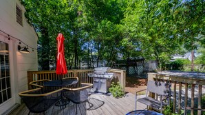 A wooden deck with outdoor furniture, including a table and chairs, and a barbecue grill. - Bama Bungalow - Book for football season and more! (Tuscaloosa)