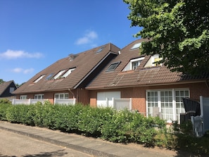 A residential building with a sloped roof, dormer windows, and a brick facade.
