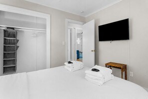A hotel room with a bed, a wardrobe, a television, and a small table. - Under the Palms | Steps to Beach, 2 Blocks to Center Street, Screened Porch + Pets Considered (Folly Beach)