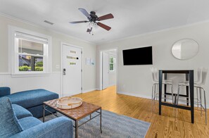 A modern living room with a ceiling fan, a TV mounted on the wall, and a seating area with a sofa and a coffee table.