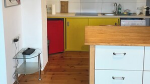 A modern kitchen with a glass table, wooden cabinets, and a red fridge. - Panoramic view of the Rhön (Bischofsheim an der Rhön)