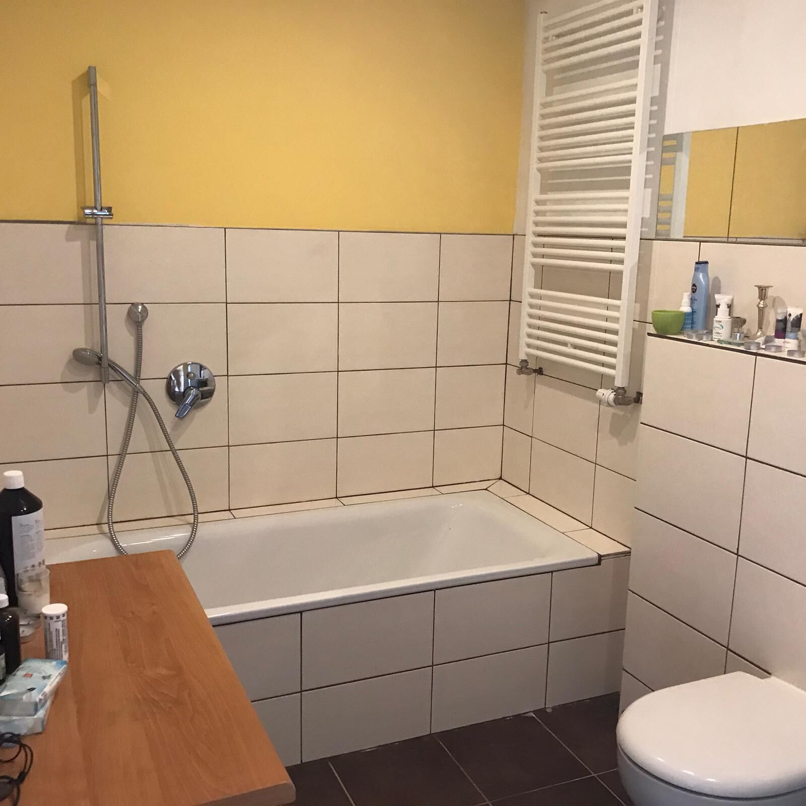 Une salle de bain avec une baignoire, des toilettes et une étagère contenant des articles de toilette.
