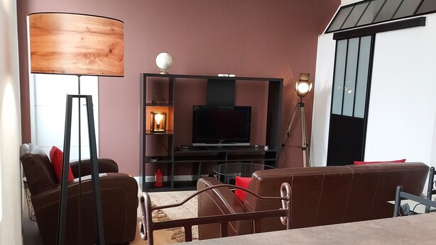 A modern living room with a flat-screen TV, a wooden floor lamp, and a sofa.