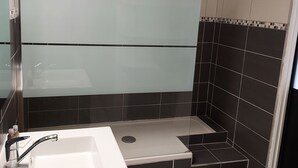 A modern bathroom with a shower, a sink, and a mirror.