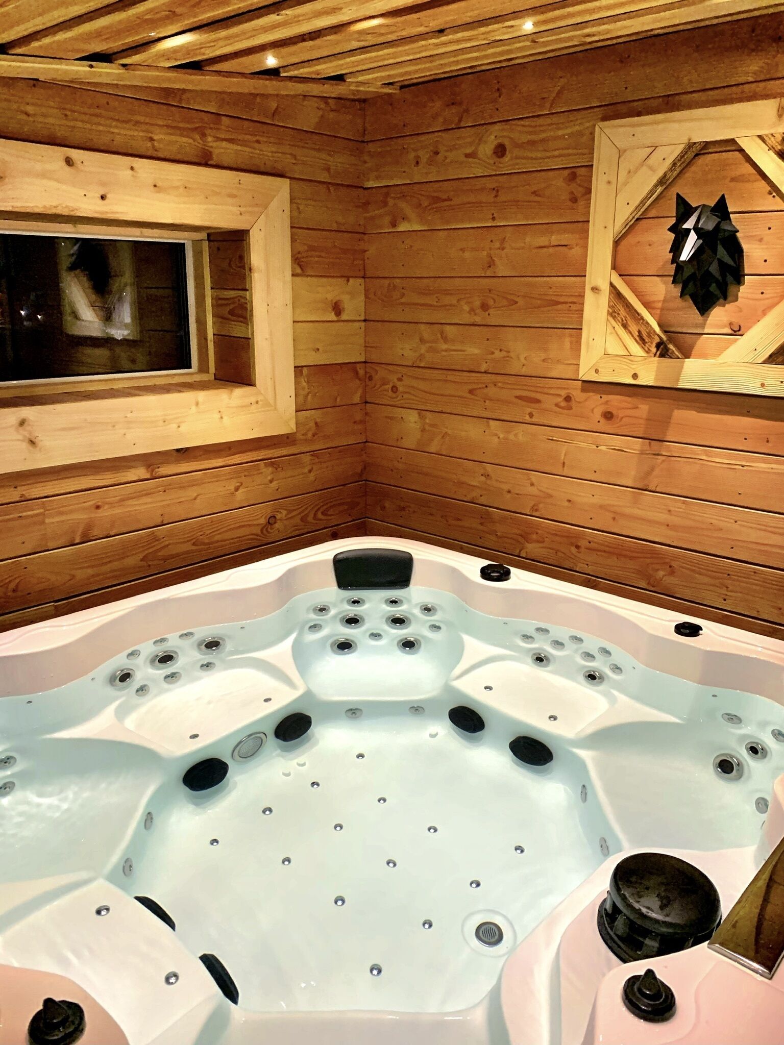A wooden cabin with a hot tub in the center.