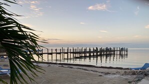 A beach with a wooden pier extending into calm waters, surrounded by sand and palm trees. - Keys Villa--Islamorada private beach! (Islamorada)