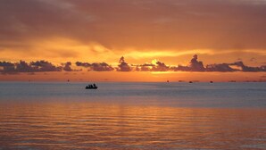 A calm sea at sunset with a boat in the foreground and distant ships on the horizon. - Keys Villa--Islamorada private beach! (Islamorada)