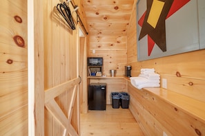 Un piccolo chalet in legno con angolo cottura, completo di microonde, frigorifero e lavello.