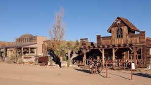 A rustic Western-style building with a pottery shop sign, wooden structures, and a large wheel. - Pioneertown Bohemian Getaway! (Pioneertown)