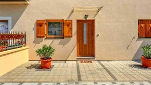 A building with a wooden door, a window with shutters, and a potted plant in the foreground.