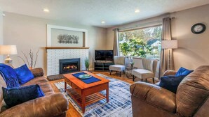 A living room with a fireplace, leather sofas, a coffee table, and a TV.