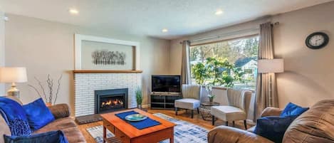 A living room with a fireplace, leather sofas, a coffee table, and a TV.