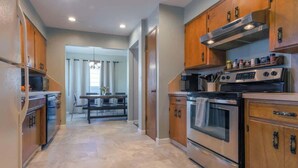 A modern kitchen with wooden cabinets, stainless steel appliances, and a dining area with a table and chairs.