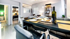 Un comedor moderno con una mesa negra, platos blancos y una botella de vino.