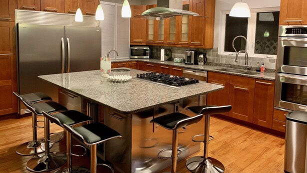 A modern kitchen with wooden cabinets, stainless steel appliances, a granite countertop, and bar stools. - MODERN MASSIVE LARGE GROUP 3800sf MIT HARVARD BOS (Somerville)