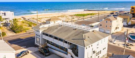 A multi-story building with a parking area and a view of the beach.